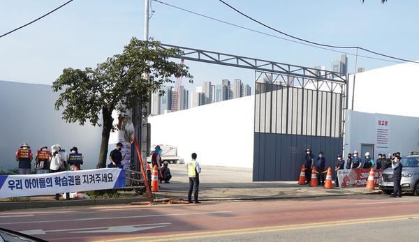 지난 7월 광명시 철산동 도덕초등학교 증개축 공사 현장 앞에서 학부모들(왼쪽)과 전국건설노조 경기중서부건설지부가 각각 집회를 하고 있다.