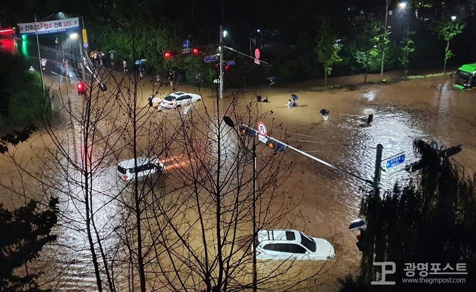 지난 8일 오후 10시쯤 광명시 철산동 광명성애병원 앞 한 도로가 폭우로 침수되면서 차량들이 빗물에 잠겨있다. 또한 시민들이 허리까지 찬 빗물을 뚫고 도로를 건너고 있다./시민 제공